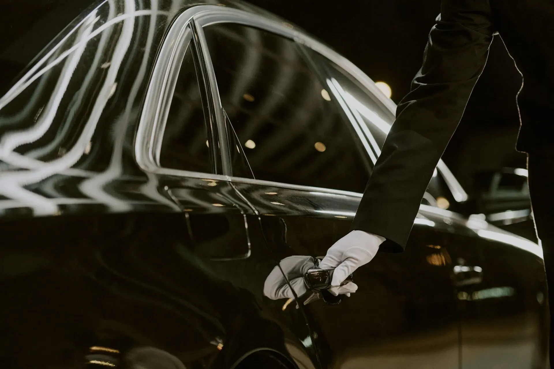 Chauffeur opening the door of a black executive sedan for a planned airport transfer